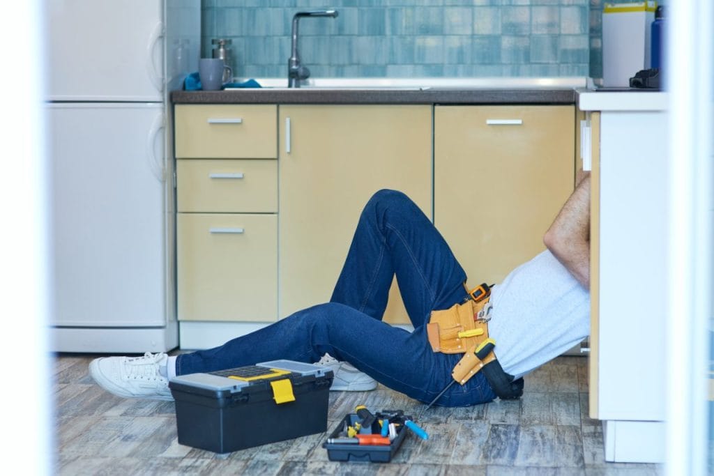 reliable-service-professional-repairman-plumber-examining-and-fixing-sink-pipe-in-the-kitchen